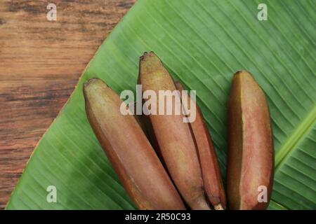 Köstliche lila Bananen und frisches Blatt auf Holztisch, flach liegend Stockfoto