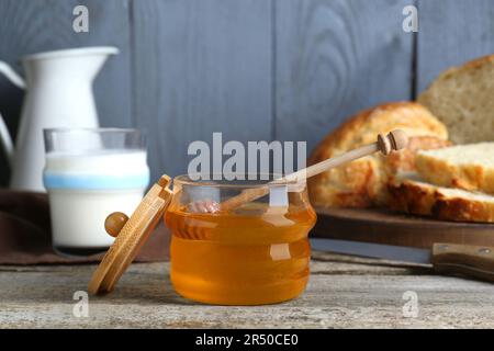 Glas Honig, Milch und Brot auf einem rustikalen Holztisch Stockfoto