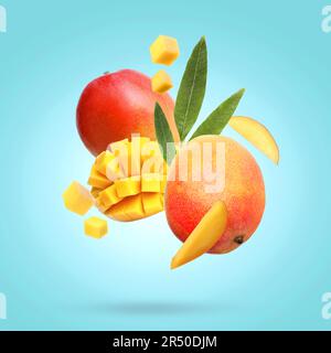 Köstliche Mangofrüchte und Blätter auf türkisfarbenem Hintergrund Stockfoto