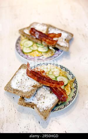 Omelett mit Gurkenscheiben, Speck und Toast mit Frischkäse Stockfoto