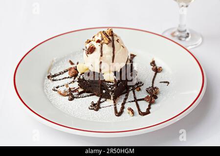 Schokoladenbrownie garniert mit Vanilleeis und Pekannüssen Stockfoto