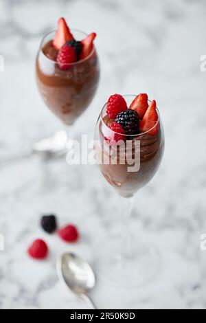 Schokoladenmousse garniert mit Erdbeeren und Himbeeren, serviert in einem Champagnerglas Stockfoto