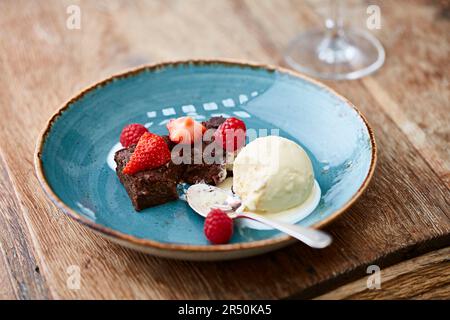 Schokolade-Brownie mit Erdbeeren und Himbeeren mit einem Vanilleeis gekrönt Stockfoto