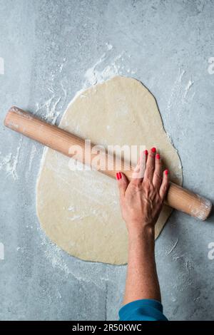 Den Teig für Tarte Flambée ausrollen Stockfoto