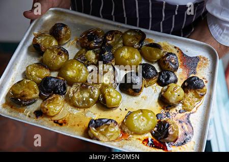 Tomatillos auf einem Metalltablett rösten, das für Salsa verde vorbereitet wird Stockfoto