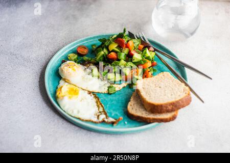 Gesundes Mittagsset mit Spiegeleiern und frischem Gemüsesalat auf dem Teller Stockfoto