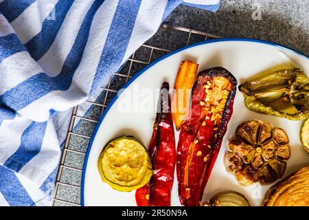 Gesundes Abendessen mit verschiedenen Grillgemüse auf Keramik-Geschirr mit saurer Rahmsoße serviert Stockfoto