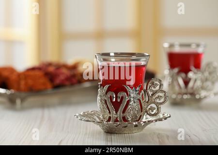 Ein Glas traditioneller türkischer Tee im alten Halter auf einem weißen Holztisch Stockfoto