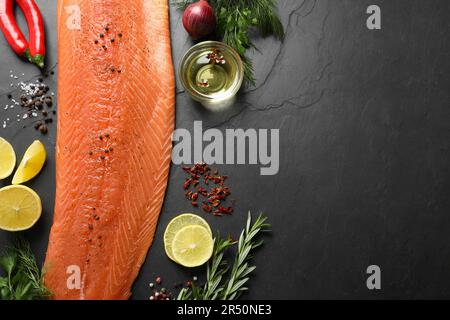 Frischer roher Lachs und Zutaten für Marinade auf schwarzem Tisch, flach liegend. Platz für Tex Stockfoto