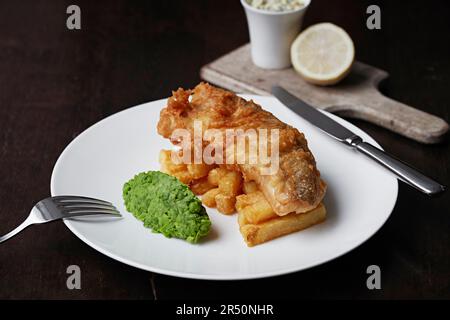 Mit Bier gemahlener Fisch und Pommes Frites mit Erbsen Stockfoto