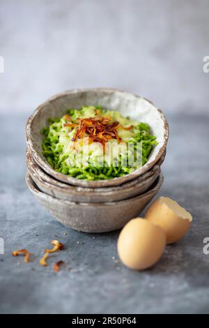 Kräuterspaetzle mit Emmentalkäse und gebratenen Zwiebeln (vegetarisch) Stockfoto