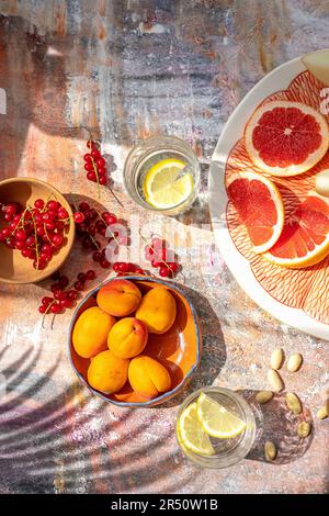 Aprikose, rote Strömungen, rote Grapefruit und Mandel mit Gläsern aromatisiertem Wasser Stockfoto