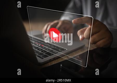 Mann spielt Videomedien, während er sich ein Webinar auf einem Laptop ansieht, oder Bildschirmtechnologie-Schnittstelle Kommunikation Anruf zukünftiges Meeting-Video Stockfoto