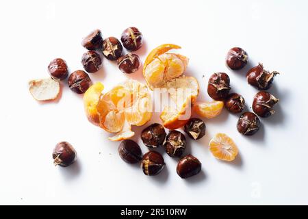 Flach liegend mit gerösteten Kastanien und Clementinen auf weißem Hintergrund Stockfoto