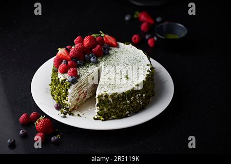 Matcha-Mille-Feuille-Kuchen mit Pistazien und Sommerbeeren Stockfoto