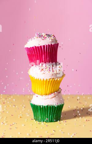 Drei Cupcakes mit Buttercreme und Streuseln in verschiedenen Pappbechern Stockfoto