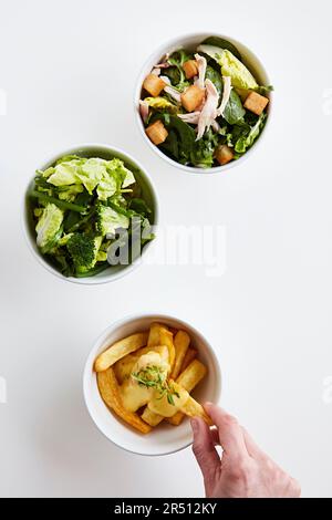 Drei verschiedene Beilagen: Gemischter Blattsalat mit Hühnchen und Croutons, gemischter Blattsalat mit Gemüse und Pommes frites Stockfoto