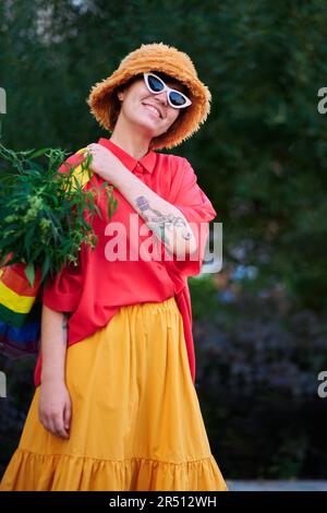 Leuchtend aussehende Frau in rotem T-Shirt und gelbem Rock mit LGBT-Farben Beutel voller Canabis . Hochwertiges Foto Stockfoto