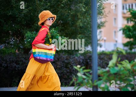 Leuchtend aussehende Frau in rotem T-Shirt und gelbem Rock mit LGBT-Farben Beutel voller Canabis . Hochwertiges Foto Stockfoto