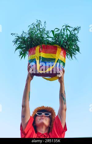 Leuchtend aussehende Frau in rotem T-Shirt und gelbem Rock mit LGBT-Farben Beutel voller Canabis . Hochwertiges Foto Stockfoto