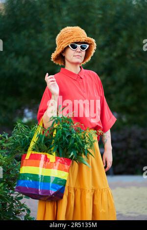 Leuchtend aussehende Frau in rotem T-Shirt und gelbem Rock mit LGBT-Farben Beutel voller Canabis . Hochwertiges Foto Stockfoto