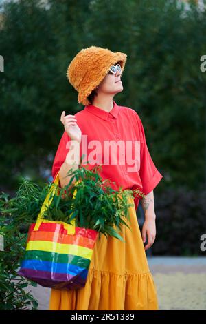 Leuchtend aussehende Frau in rotem T-Shirt und gelbem Rock mit LGBT-Farben Beutel voller Canabis . Hochwertiges Foto Stockfoto