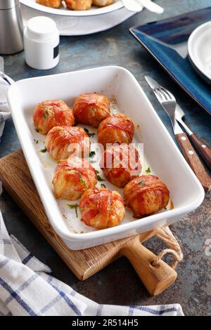 Gebackene Hühnerbällchen, in Scheiben geräucherten Speck verpackt Stockfoto