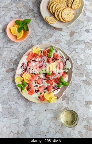 Rote-Bete-Lachs-Brett mit Zitrone, roten Zwiebeln, Kapern auf einem Bett aus Labna Stockfoto