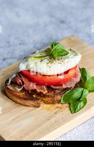 Offenes, geröstetes Sandwich mit Serrano-Schinken, Rindtomaten und Burrata Stockfoto