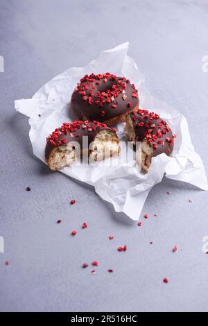 In Schokolade getauchte Donuts, garniert mit gefriergetrockneten Erdbeeren Stockfoto