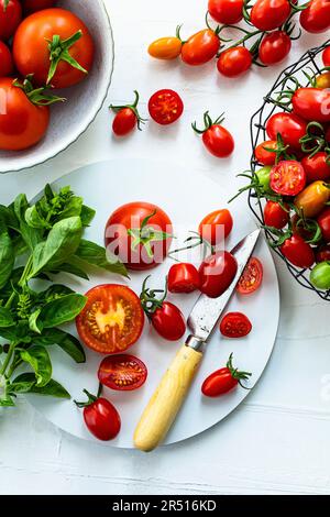 Gemischte Tomaten in Schüsseln und auf einem Schneidebrett Stockfoto