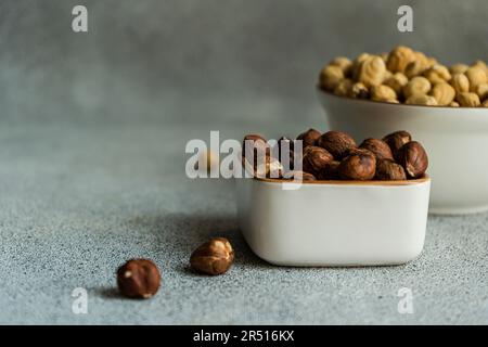 Schüssel voll mit Haselnüssen auf Betonhintergrund Stockfoto