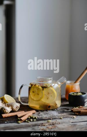 Würziger Wintertee mit Zitrone, Zimt und Kardamom in Glasteekanne Stockfoto