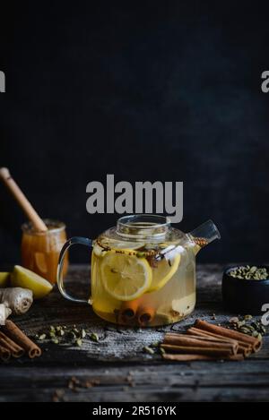 Würziger Wintertee mit Zitrone, Zimt und Kardamom in Glasteekanne Stockfoto
