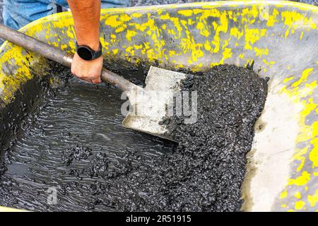 Nahaufnahme eines Arbeiters, der mit einer Schaufel Terrazzo-Pflaster von einer Schubkarre schaufelt. Walk of Fame im Bau. Stockfoto