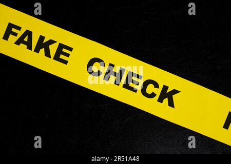 Vorsichts- und Warnkonzept für gefälschte Schecks. Gelbes Absperrband mit Wort auf dunkelschwarzem Hintergrund. Stockfoto