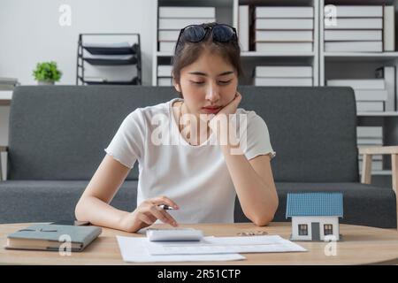 Junge Frau sitzt zu Hause am Schreibtisch und verwaltet die Haushaltsfinanzen, um Rechnungen mit einem Rechnerrechner zu bezahlen. Weibliche Pflege von Budget Smartphone für verwenden Stockfoto