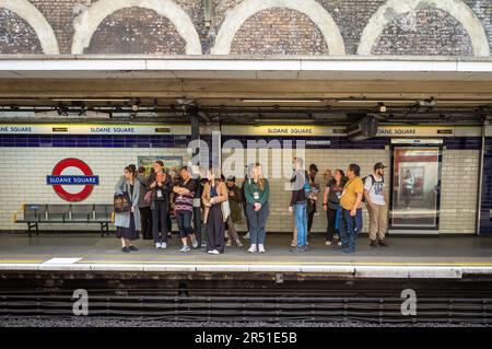 Eine Gruppe von Personen wartet auf einen U-Bahn-Zug auf dem Bahnsteig an der Sloane Square U-Bahn-Station in London. Stockfoto