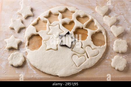 Das Schneiden von Hüttenkäsekeksen mit Schimmelpilzen aus Weichteig, der auf einem Brett gerollt wird. Köstliche hausgemachte Kuchen Stockfoto