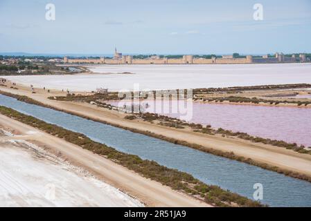 Pink Salt Sumpflandschaft bei Aigues-Mortes, Frankreich. Mittelalterliche Stadt Aigues Mortes mit gut erhaltener Mauer, Stadtmauern und Türmen Stockfoto