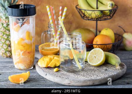 Zutaten eines Mango-Zitrus-Smoothies in einem Mixerbehälter, bereit zum Mischen. Stockfoto