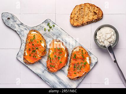 Essensfotografie mit Toast mit geräuchertem Lachs, Frischkäse, Kressensalat, Frühstück, Sandwich, Bruschetta, Filet, Scheibe, Fisch und Meeresfrüchte Stockfoto