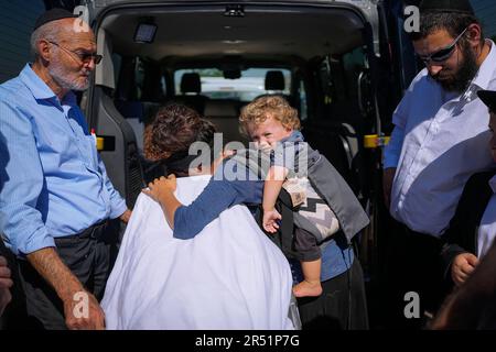 Tal Tamari carries her son as she mourns over the body of her husband ...