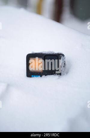 Action-Kamera im Schnee mit Sonnenuntergang auf dem Bildschirm Stockfoto