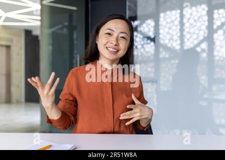 Webcam-Ansicht, glückliche asiatische Geschäftsfrau, die lächelt und in die Kamera schaut, Videoanrufe mit Kollegen, Remote-Meeting, weibliche Mitarbeiterin in modernen Büros. Stockfoto