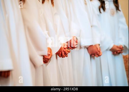 Unschuld in Weiß: Kinderhände im Gebet in der Kirche Stockfoto