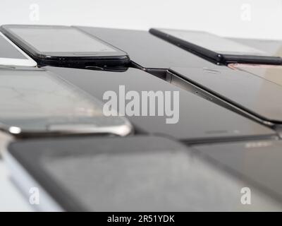 Beschädigte Mobiltelefone. Ein Haufen kaputter Smartphones. Benutzte Telefone mit hellem Hintergrund. Stockfoto