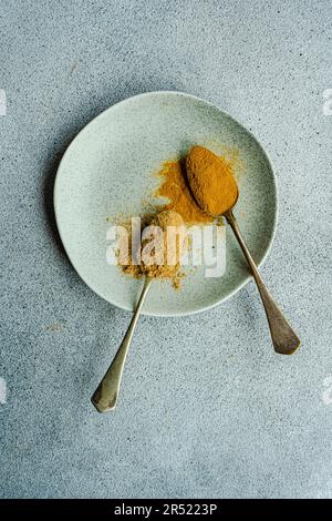 Vintage-Löffel mit pulverförmigen Gewürzen aus Ingwer und Kurkuma Stockfoto
