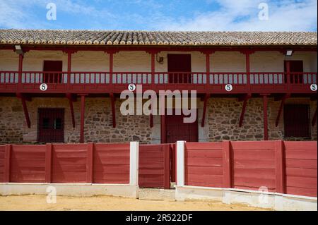 Rote Backsteinmauer mit Inschrift und Steinmauer mit Galerien der berühmten Stierkampfarena von Madrid Spanien mit gefliestem Dach unter blauem Himmel Stockfoto