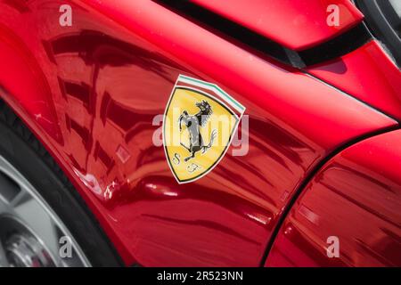 Side view of a red Ferrari brand luxury sports car with the black horse logo sticker on the body, no people Stockfoto